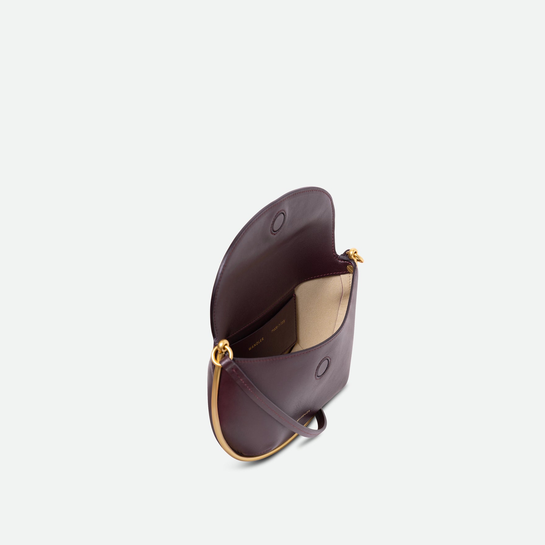Wandler Kate Mini Crossbody in the color Grape, made from Italian calf leather with golden hardware and adjustable strap, pictured from above, allowing for a glimpse into the inside of the bag.