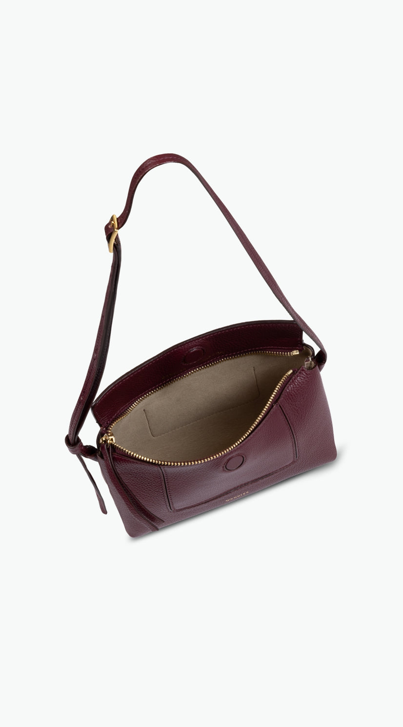 Wandler Penelope Slouch Mini in the color Acai, made from  Italian calf leather with golden hardware and slim adjustable strap, pictured with the bag being open allowing for a glimpse into the inside.