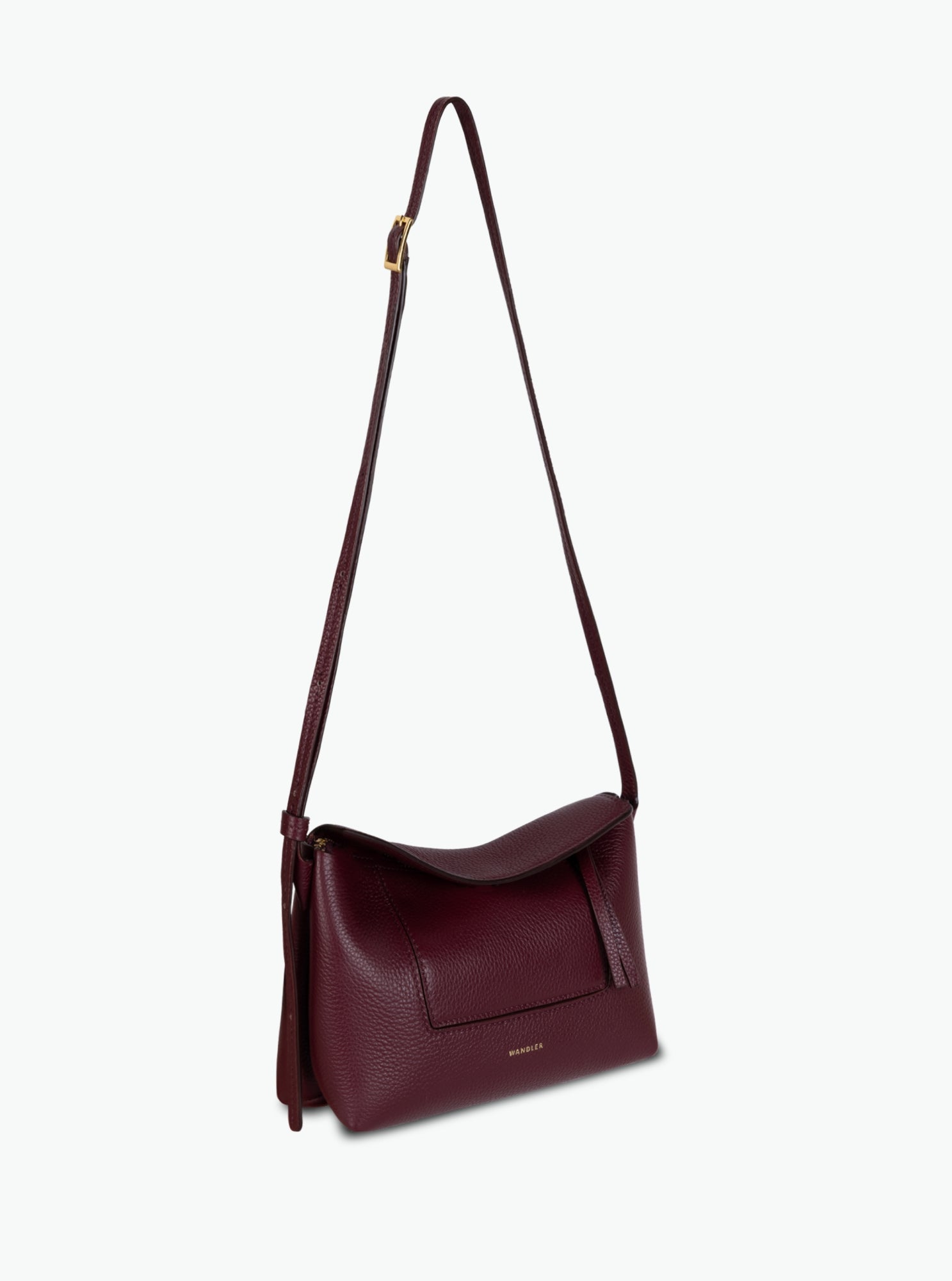 Wandler Penelope Slouch Mini in the color Acai, made from  Italian calf leather with golden hardware and slim adjustable strap, pictured with the straps suspended into the air.