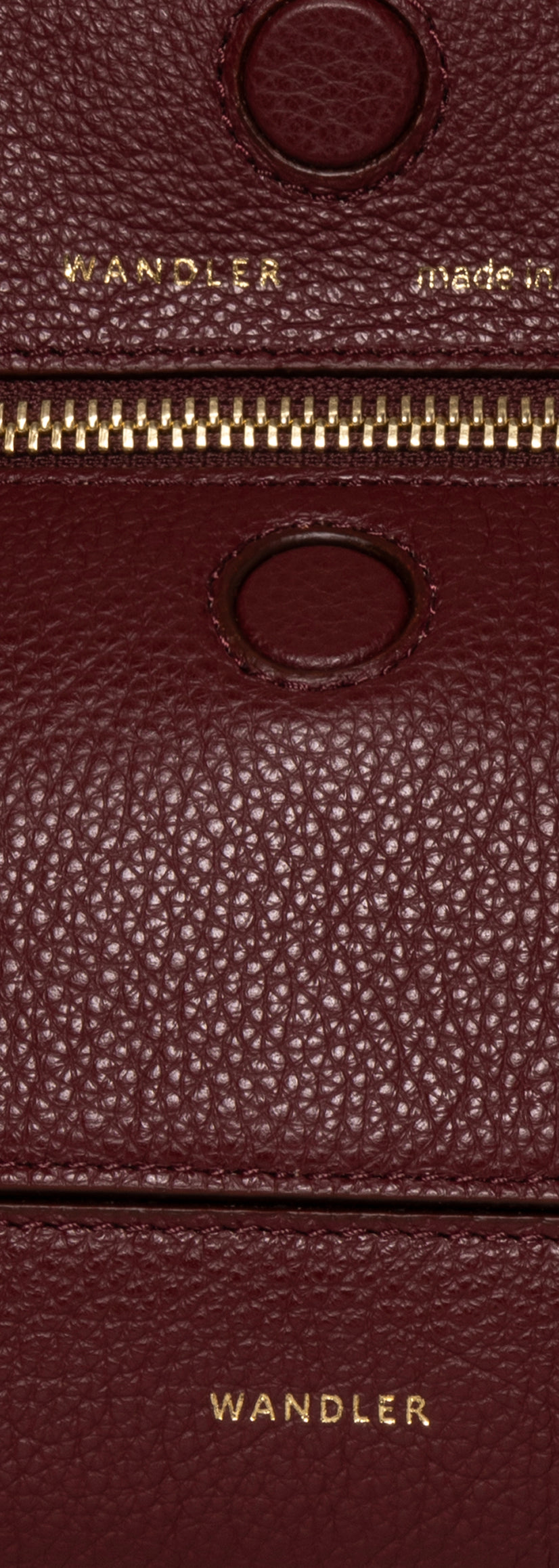 Wandler Penelope Slouch Mini in the color Acai, made from  Italian calf leather with golden hardware and slim adjustable strap, close up detailing the leather and logo.