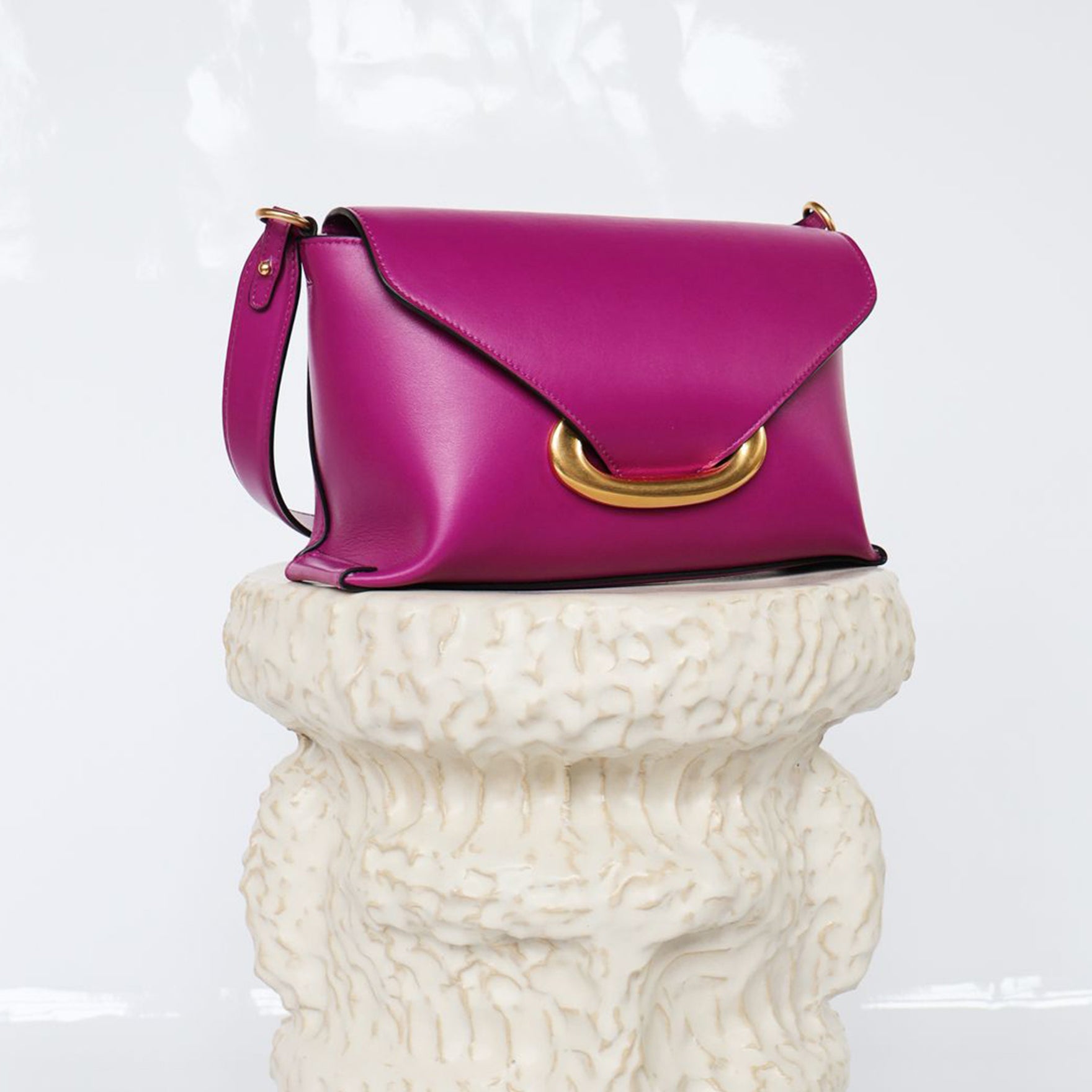 Wandler Veneto Shoulder Bag Small in the color Cobra, made from Italian calf leather with oversized golden clasp hardware, structured silhouette, pictured on pillar.