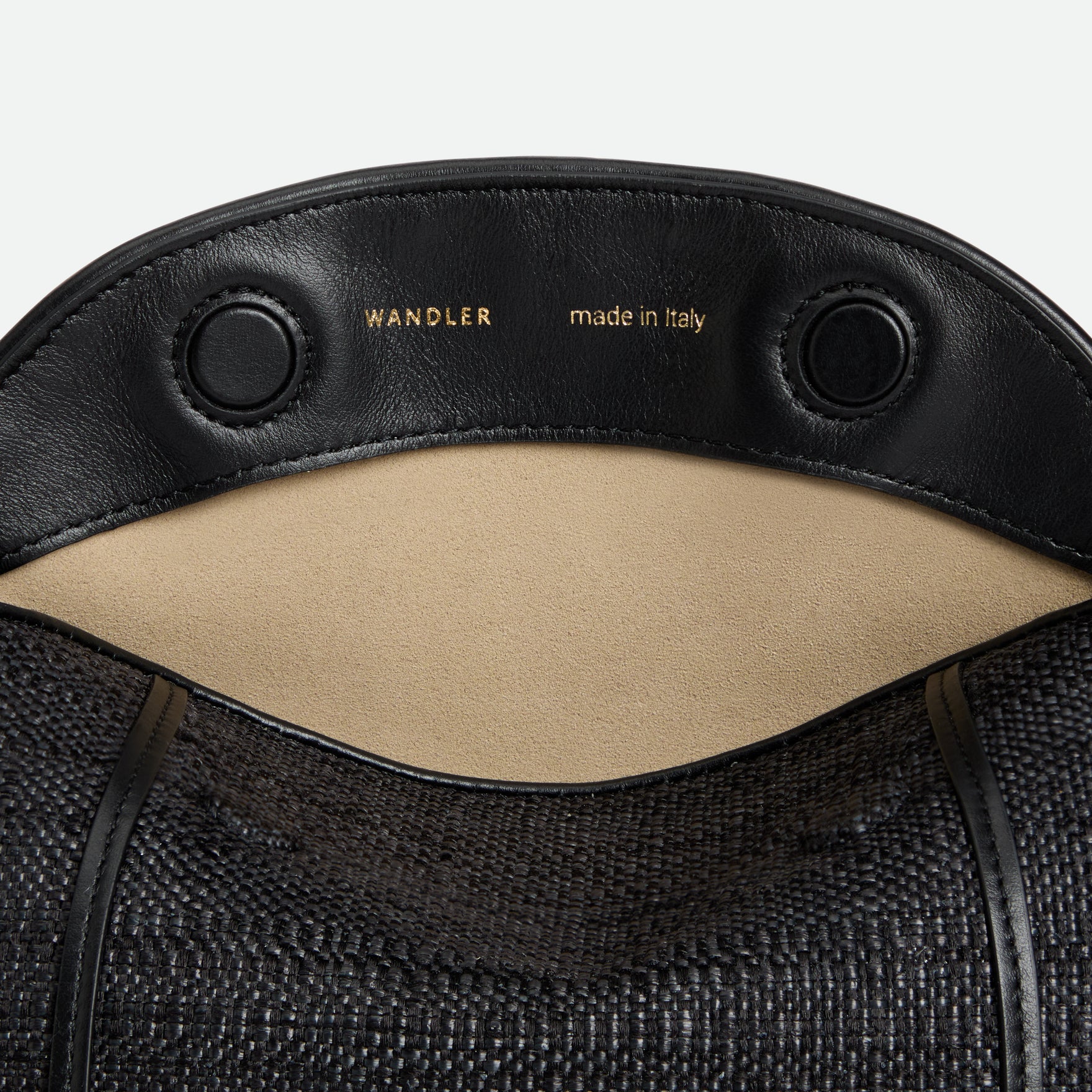 Wandler Penelope Slouch Bag in the color Black Raffia, made from raffia and smooth calf leather with golden hardware and adjustable slim strap, close up shot, bag is pictured with the flap open detailing the Wandler logo.