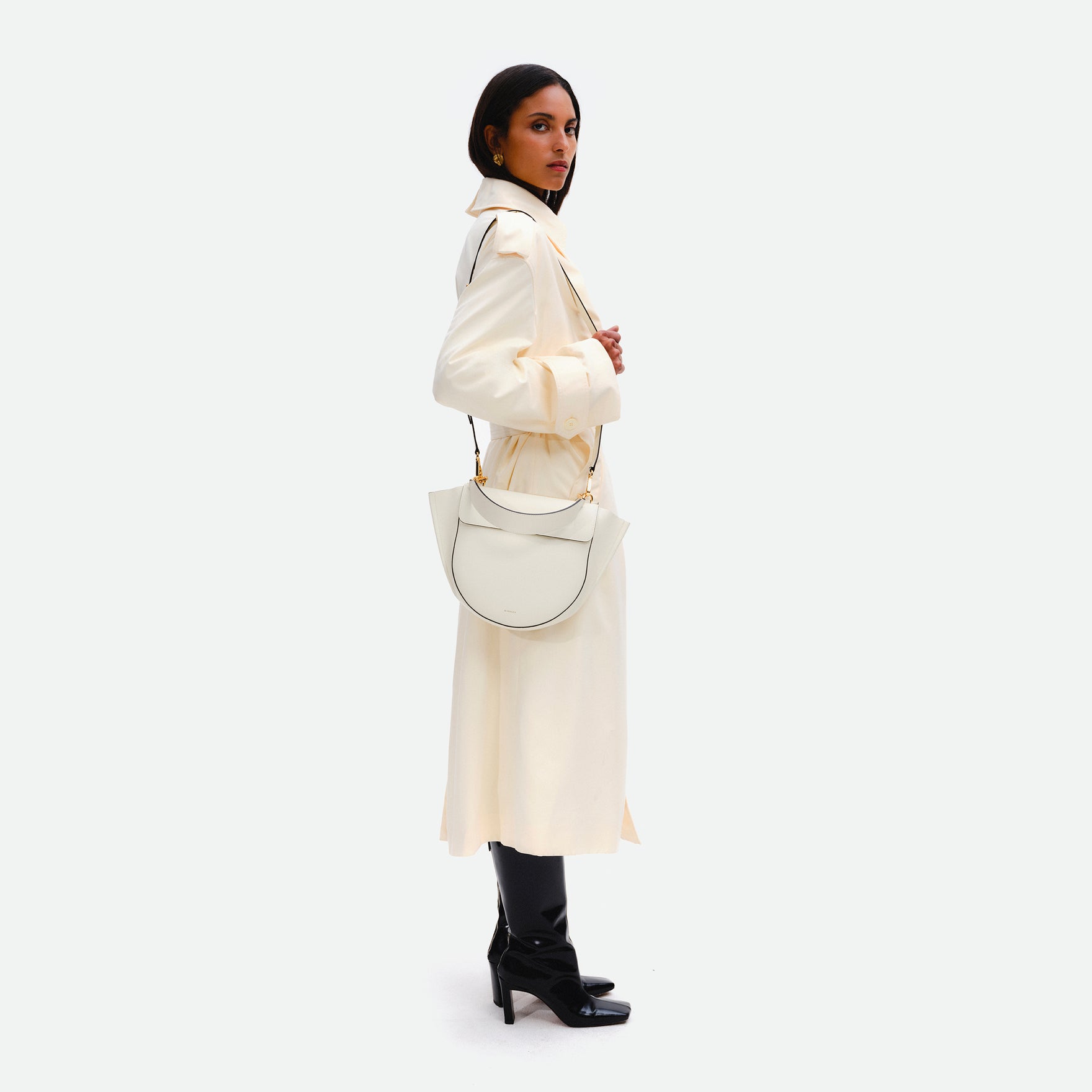 Wandler Hortensia Bag Medium in the color luck, white, made from Italian calf leather with golden hardware, rounded silhouette and top handle, pictured on model, worn on the shoulder, full body view. 