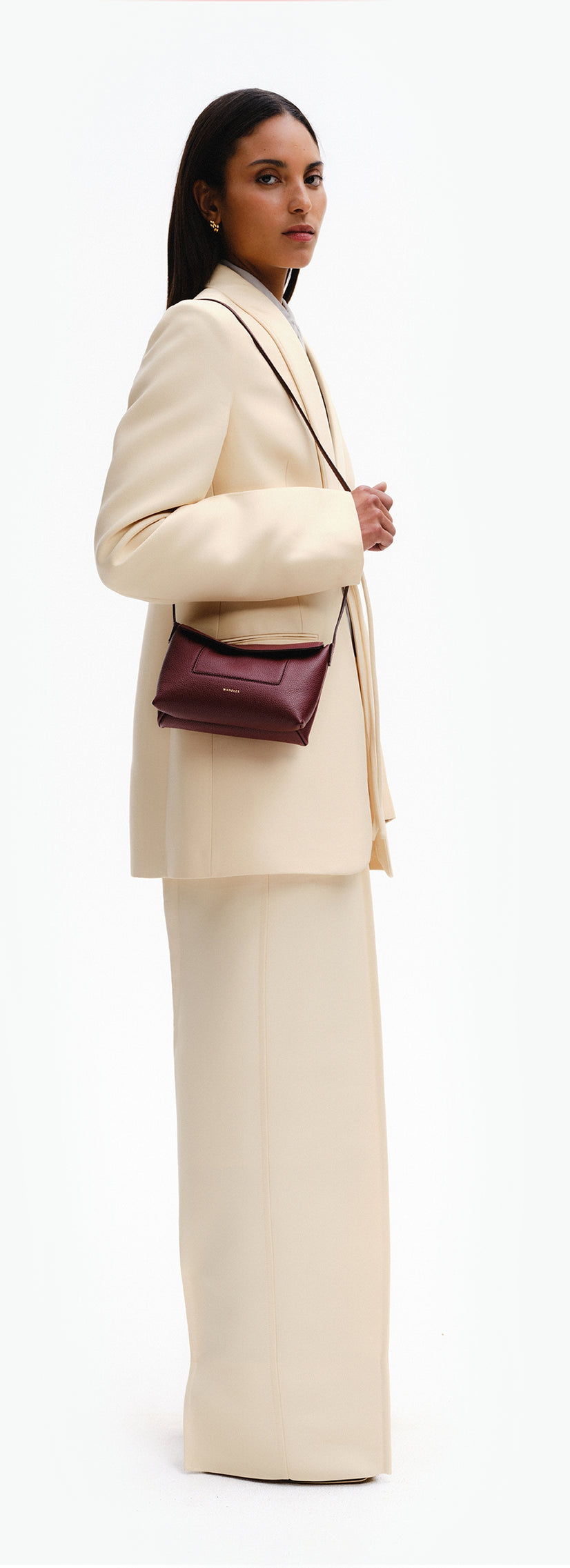 Wandler Penelope Slouch Mini in the color Acai, made from  Italian calf leather with golden hardware and slim adjustable strap, pictured being worn on the shoulder by model.