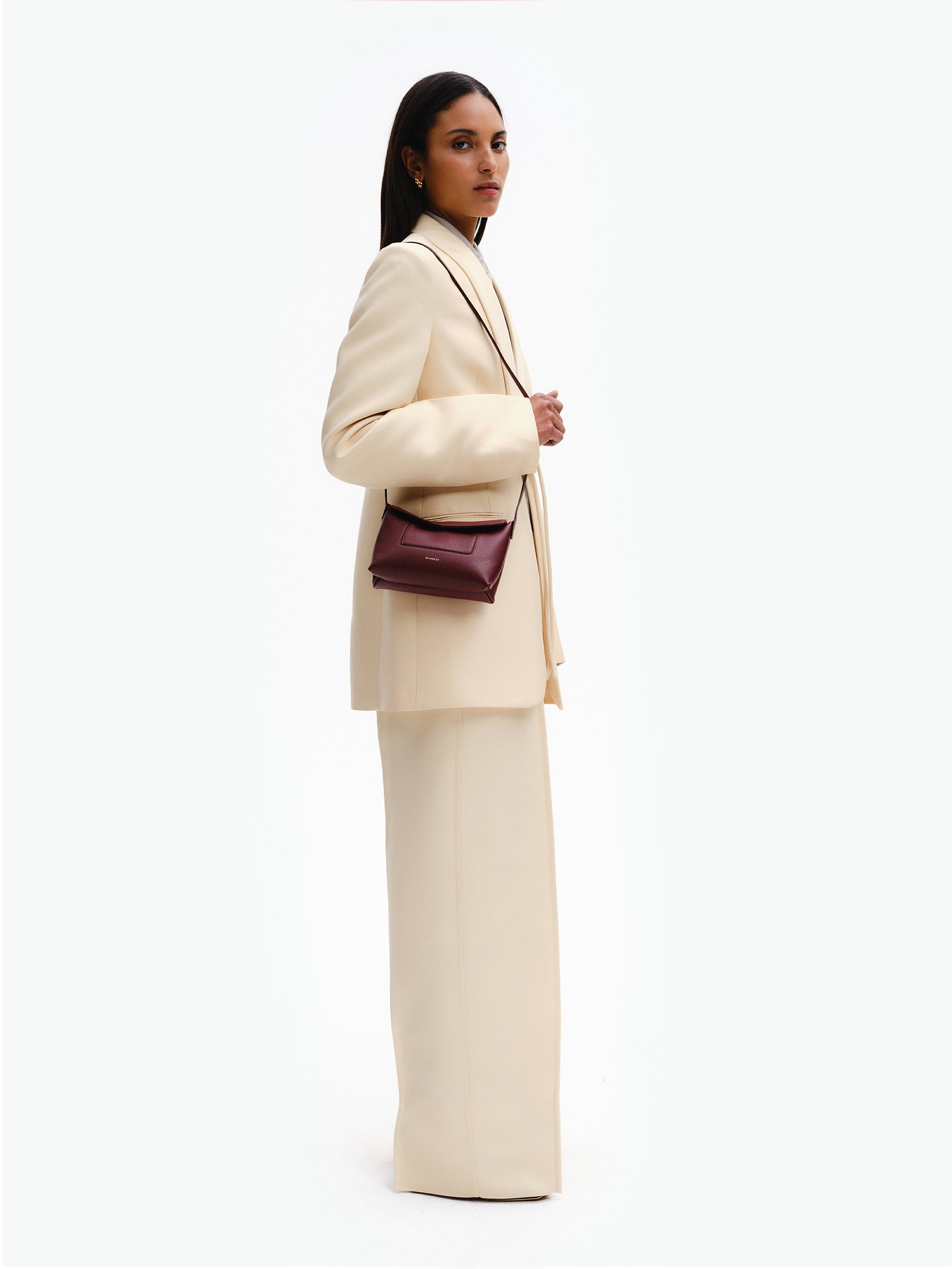 Wandler Penelope Slouch Mini in the color Acai, made from  Italian calf leather with golden hardware and slim adjustable strap, pictured being worn on the shoulder by model.